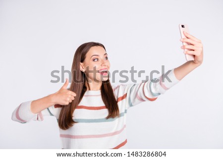 Pretty lady making selfie on new telephone raising thumb up wear striped pullover isolated white background