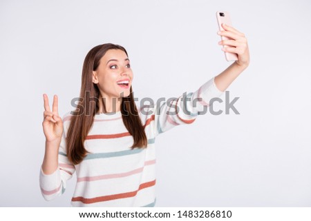 Pretty lady making selfie on new telephone showing v-sign symbol wear striped pullover isolated white background