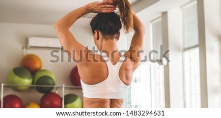 Fitness instructor in the sport room background. Female model with muscular fit and slim body. Sport concept
