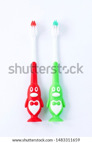 Children's toothbrushes in a form of red and green penguins on a white background isolated. Kids oral care, first deciduous teeth hygiene, bathroom supplies, dentistry.