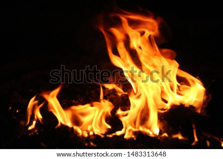 A small fire that burns the garbage behind the house on a black background