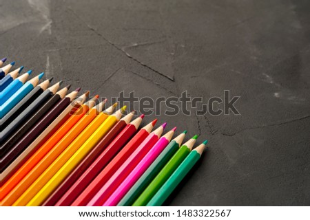 Close-up of bright sharpened pencils lie on the colors of the rainbow on a black background side by side. The concept of children's creativity and preparation for school. Copyspace