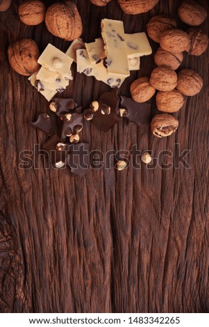 Nuts and milk and dark chocolate pieces on wooden background