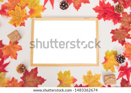Selective focus flat lay top view Autumn template concept, colorful maple leaves, little lovely gift boxes and dry pine cone on isolated white background with blank mock up wooden picture frame