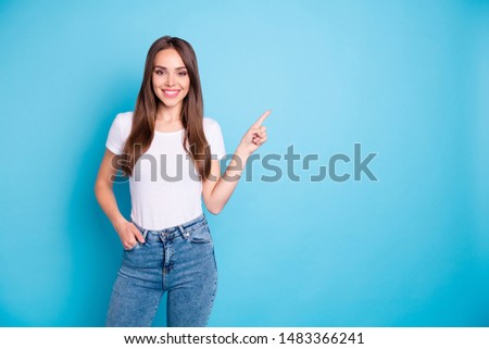 Portrait of charming confident person showing adverts pointing at copy space wearing white t-shirt denim jeans isolated over blue background