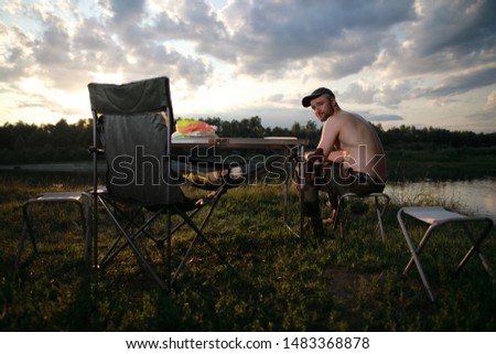 Caucasian man enjoying on hike picnic near river and forest with beautiful sky clouds 