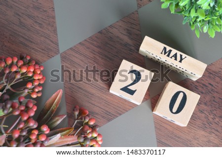 May 20. Date of May month. Number Cube with a flower leaves and bush on Diamond wood table for the background