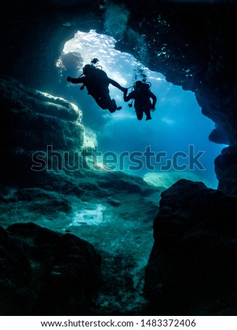 scuba divers entering a cave