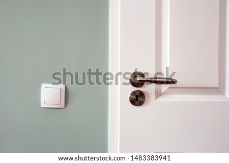 Modern white door with chrome door handle and light switch, new clean design retro Royalty-Free Stock Photo #1483383941