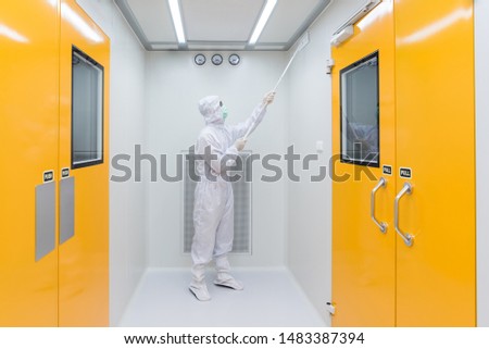 A scientist in sterile coverall gown using Cleaning tool for cleaning laboratory. Cleanroom facility. Royalty-Free Stock Photo #1483387394