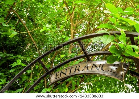 Entrance sign hanging over open garden gate.