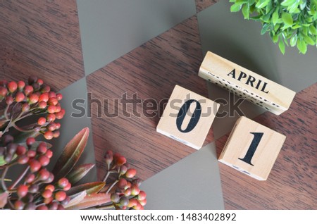 April 1. Date of April month. Number Cube with a flower leaves and bush on Diamond wood table for the background