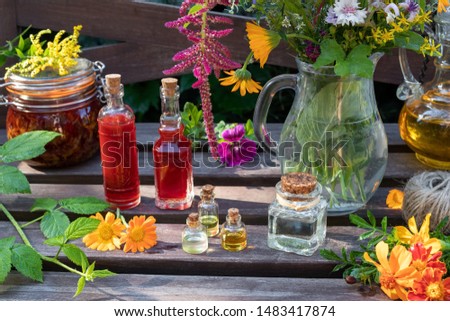 Bottles of essential and herbal oils with calendula, Tagetes patula, goldenrod and other medicinal herbs