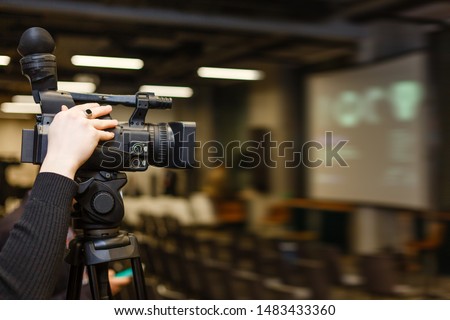 Camera man recording event with professional video camera Panasonic. Blurred background