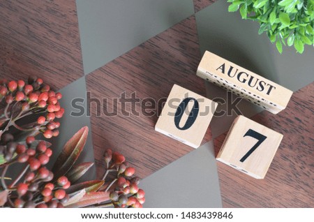 August 7. Date of August month. Number Cube with a flower leaves and bush on Diamond wood table for the background