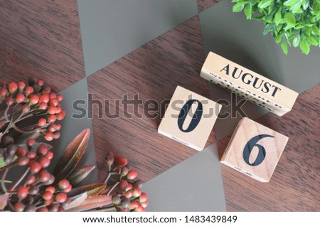 August 6. Date of August month. Number Cube with a flower leaves and bush on Diamond wood table for the background