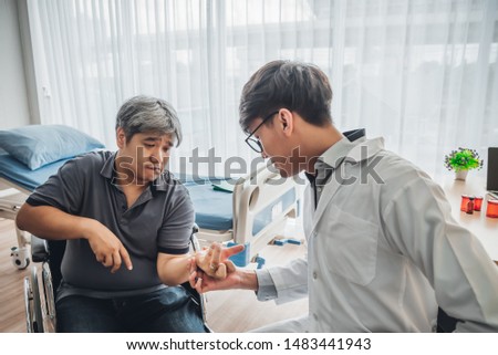 Asian male doctor is checking the hand with a kink of middle aged male patients Which is a neurological disease or hemiplegia at hospital, to health care and health insurance concept. Royalty-Free Stock Photo #1483441943