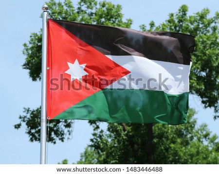 national flag of Jordan waving on the wind in the blue sky					