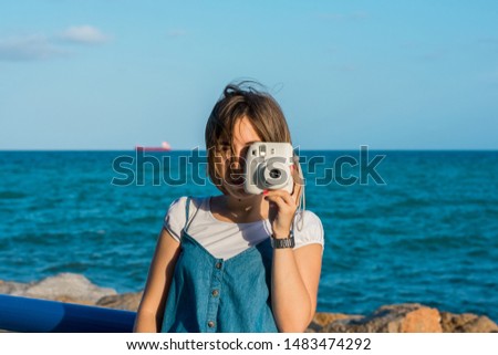 Young woman with a instant camera in the coast of Alicante, Spain. Lifestyle concept, leisure.