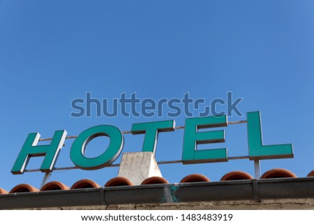 Sign Hotel. Green letters in the blue sky.