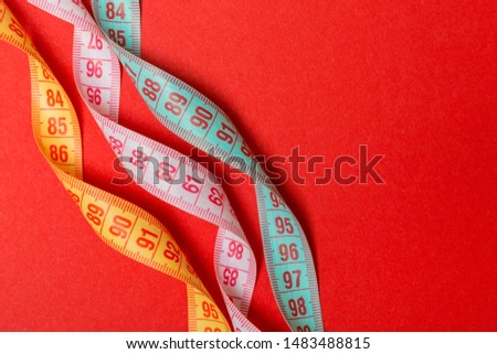 Close up of colorful measure tapes on red background. Perfect female figure measurements concept.