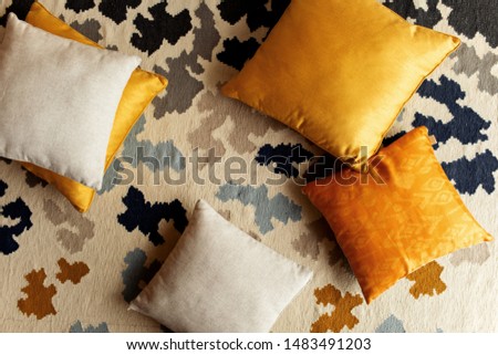 Natural cotton eco orange and yellow pillows on modern carpet at home. Detail of cozy autumn interior. Zero waste concept.