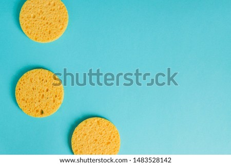 yellow round sponges on pastel blue background, Facial care. Cosmetic device. Deep skin cleansing.