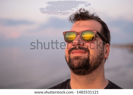 Man with sunset reflecting in his sunglasses