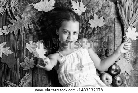 Kid girl smiling face relax wooden background autumn attributes top view. Child with long hair with autumn maple leaves. Autumn coziness is just around. Tips for turning autumn into best season.