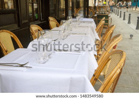 Close up of several served tables with white tablecloths and ward chairs, selective focus