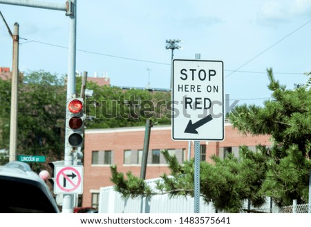 Stop Here on Red, traffic sign on a city street, attached to a signpost and made in white and black color