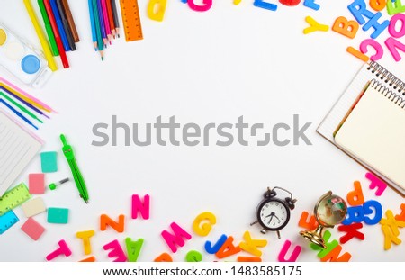 multicolored plastic letters of the English alphabet, stationery school supplies, alarm clock on a white background, copy space
