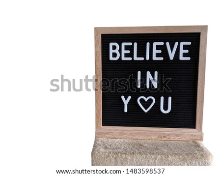 Text in english spelling Believe in You on a black felt sign board in a wooden frame.