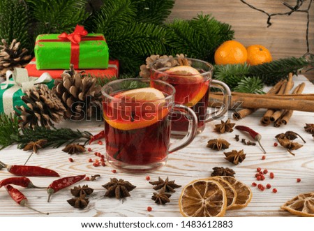 Red winter drink with spices on festive new year background. Mulled wine or Christmas tea with cinnamon, red pepper, anise and lemon on rustic woden background
