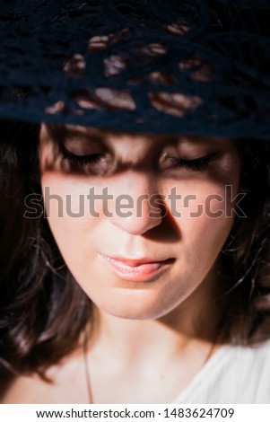 Beautiful woman in hat. Pretty young woman with a shadows pattern on face. Closed eyes. Light and shadow