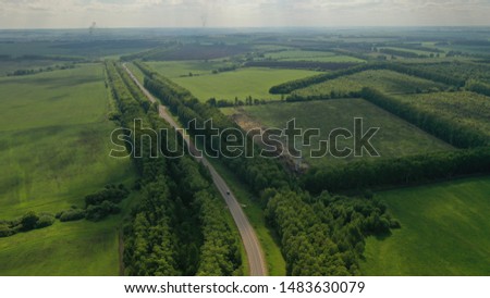Lonely road in Russia surrounded by cultivated fields. Summer aerial shot