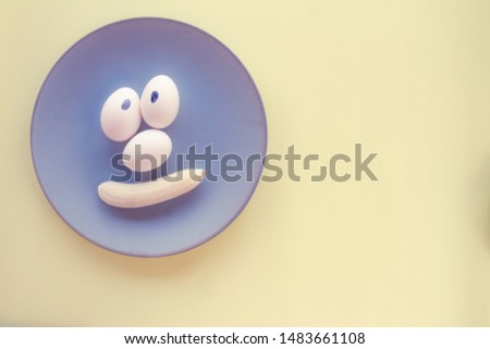 Funny face made with food. Eggs forming eyes. Mouths shaped like bananas. Food humanization. Neutral background. Free space to write. Conceptual image