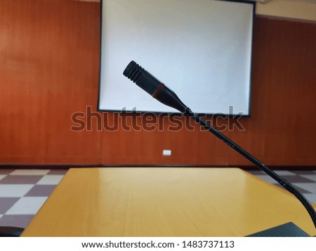 ฺBlack Microphone on wooden desk for talking or presentation in conference or meeting room with white projector board blurred background - Device and Tool