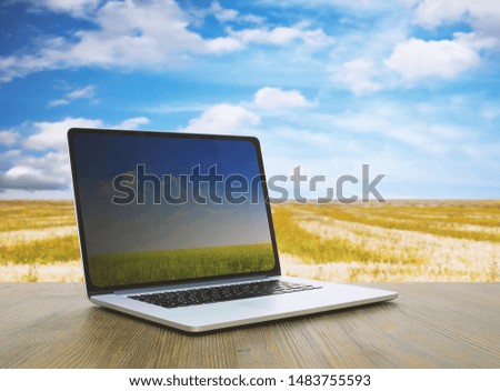 pc on wooden table, fields background