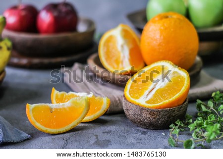 Photo of fresh orange on retro background. A slice of orange with green leaves. Half of orange on wooden plate bowl. Free space for text. Dark background. Image