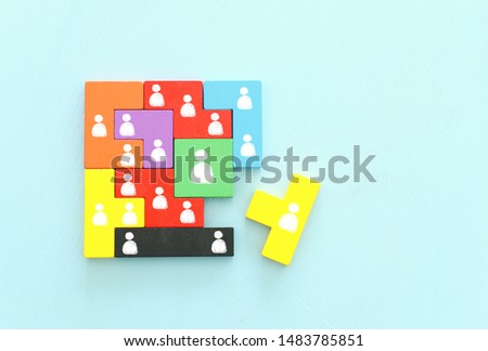 business concept image of tangram puzzle blocks with people icons over wooden table ,human resources and management concept