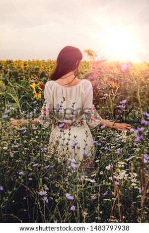 
A girl stands with her back in a field of sunflowers at sunset. Summer. Autumn.
