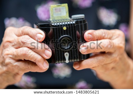 Senior woman's hands holding Retro film photo camera, Black colour, Close up shot, Selective focus, Travel concept