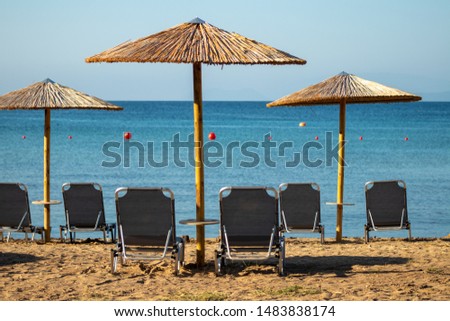 Empty Mediterranean beach with chairs and umbrellas during a early morning Summer day. The picture was taken in Mainland Greece in August 2019.