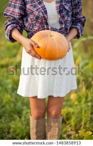 Woman with a ripe pumpkin in a garden. Autumn harvest. Autumn concept