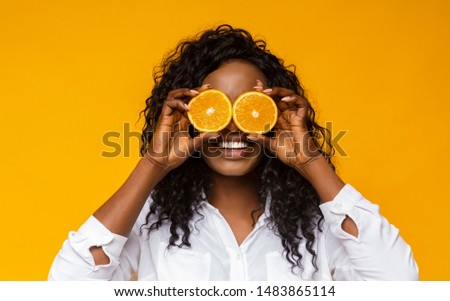 Healthy summer concept. Cheerful afro woman holding oranges near eyes, panorama Royalty-Free Stock Photo #1483865114