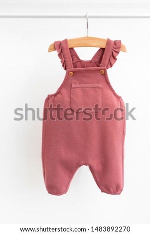 Baby-girl pants hanging on shoulders  isolated on white background for spring and autumn wardrobe/ Baby clothes