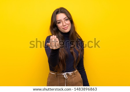 Teenager girl over isolated yellow wall inviting to come with hand. Happy that you came