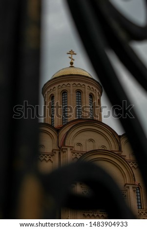 Beautiful, gorgeous, wonderful, magnificent Temple of St. Michael the Archangel, shot through the fence on the background of cloudy, overcast, covered with clouds of the sky