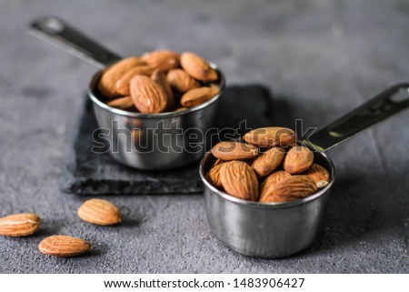 Photo of almond in the bowl on dark background. Almond with spoon or scoop. Raw whole almond. Almond concept with copyspace. Images
